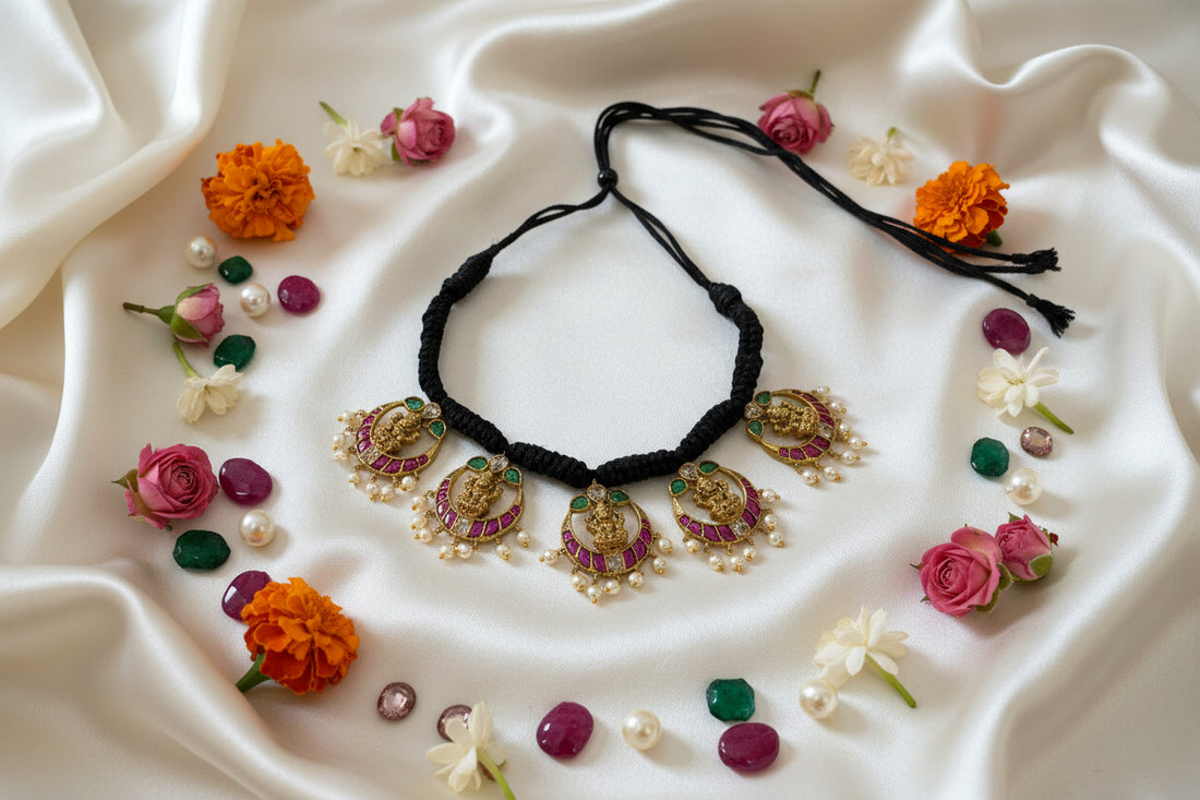 Black thread necklace with gold and red pendant on a white fabric background