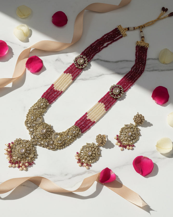 Ornate necklace and earrings set on a textured white surface