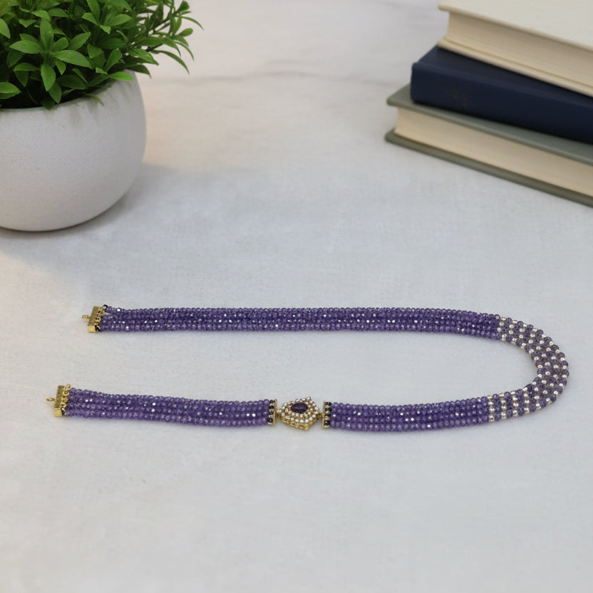 Purple beaded belt with gold accents on a light gray background