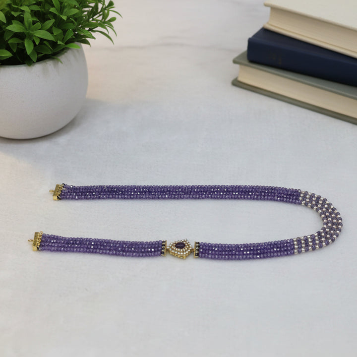 Purple beaded belt with gold accents on a light gray background