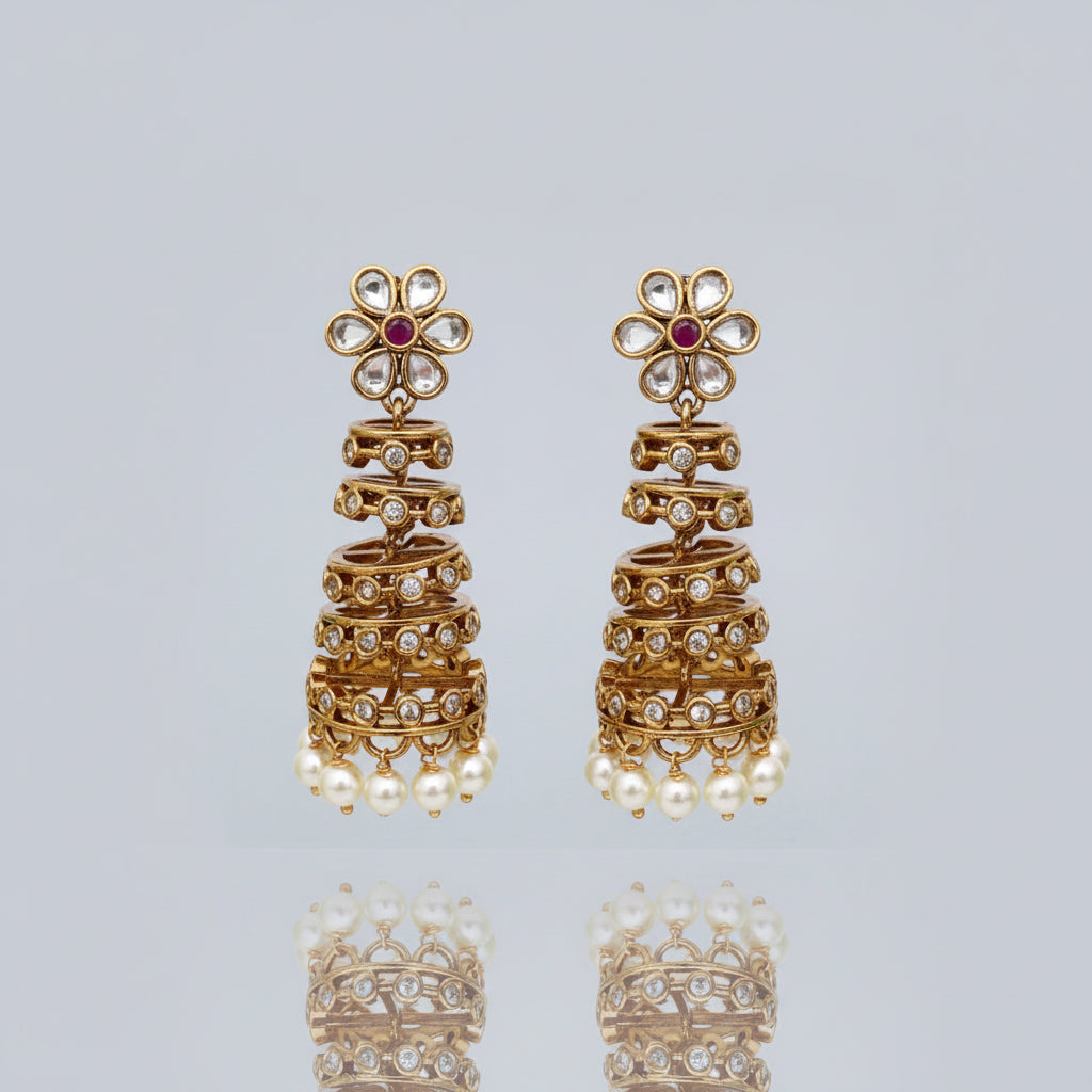 Pair of gold earrings with floral designs and pearl accents on a white background
