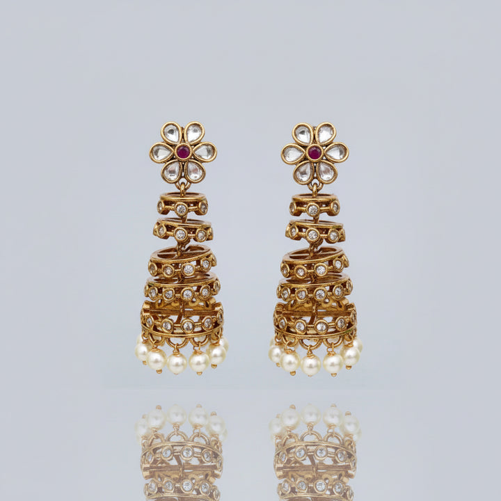 Pair of gold earrings with floral designs and pearl accents on a white background